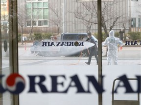 A South Korean health official sprays disinfectant in front of a building of Korean Air in Incheon on February 25, 2020.