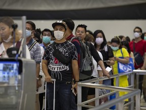 As Coronavirus spreads travelers arriving wait in line at immigration wear masks at Suvarnabhumi International airport in Bangkok, Thailand on Monday.