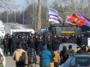 Police stand guard during a raid on a Tyendinaga Mohawk protest camp next to a railway crossing in Tyendinaga on Monday.