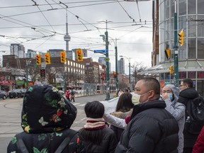 Pedestrians wear protective masks as they walk in Toronto on Monday, January 27, 2020.
