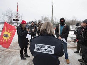 An enforcement officer reads an Injunction to members of the Tyendinaga Mohawk Territory in Tyendinaga Mohawk Territory, near Belleville as they block the CN/VIA train tracks.
