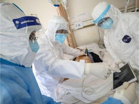 Medical workers in protective suits attend to a patient inside an isolated ward of Wuhan Red Cross Hospital in Wuhan, China February 16, 2020. China Daily via REUTERS