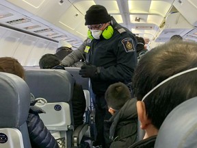 An RCMP officer wearing a mask checks Canadians who are being evacuated from China due to the outbreak of novel Coronavirus on an American charter plane.