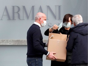 A worker holds a face mask outside the theatre where the Italian designer Giorgio Armani said his Milan Fashion Week show would take place to safeguard the health of press and buyers after a coronavirus outbreak in northern Italy, in Milan, Italy, February 23, 2020. REUTERS/Alessandro Garofalo