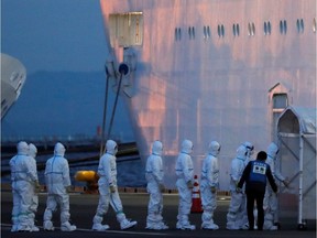 Officers in protective gear enter the cruise ship Diamond Princess, where 10 more people were tested positive for coronavirus on Thursday, to transfer a patient to the hospital after the ship arrived at Daikoku Pier Cruise Terminal in Yokohama, south of Tokyo, Japan February 7, 2020.