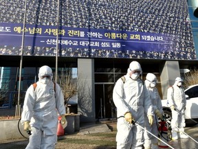 Workers from a disinfection service company sanitize a street in front of a branch of the Shincheonji Church of Jesus the Temple of the Tabernacle of the Testimony where a woman known as "Patient 31" attended a service in Daegu, South Korea, Feb. 19, 2020.