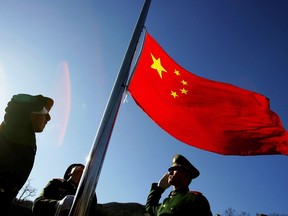 FILE: Chinese soldiers raise the national flag.