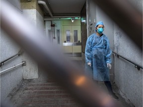 A police officer wearing protective gear stands guard behind a gate at the Hong Mei House residential building of Cheung Hong Estate in the Tsing Yi district of Hong Kong, China, in the early morning of Tuesday, Feb. 11, 2020. The Hong Kong government has evacuated some residents at a building where two patients have been confirmed to have the coronavirus infection, according to Wong Ka-Hing, controller at the Centre for Health Protection.