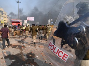 Riot police walk along a road scattered with stones following clashes between supporters and opponents of a new citizenship law, at Bhajanpura area of New Delhi on February 24, 2020, ahead of US President arrival in New Delhi.