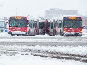 Two OC Transpo buses out of service exiting Carlingwood Mall during a heavy snowfall in Ottawa. February 27, 2020.