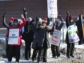 Striking teachers hold up placards in front of Vincent Massey School on Smyth Road.