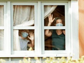 Guests wearing protective face masks look through a window at a hotel on lockdown after cases of coronavirus were detected on the Spanish island of Tenerife.