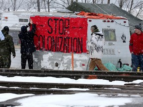 First Nations members of the Tyendinaga Mohawk Territory place a sign reading "Stop Colonization" to a camper at a blockade of train tracks servicing Via Rail, as part of a protest against British Columbia's Coastal GasLink pipeline, in Tyendinaga, Ontario on Wednesday.