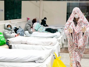 A patient at right is covered with a bed sheet at an exhibition centre in Wuhan converted into a hospital as it starts to accept patients displaying mild symptoms of the novel coronavirus.