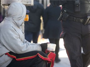 A homeless man begs for money with a plastic cup on Elgin Street.