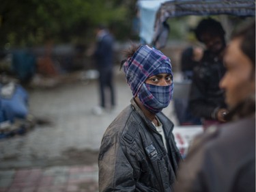 An Indian rickshaw puller wearing a scarf over his face waits for passengers to ferry them on his rickshaw amid novel coronavirus fear on March 14, 2020 in New Delhi, India.