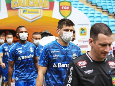 Players of Gremio enter the field wearing masks before the match between Gremio and Sao Luiz as part of the Rio Grande do Sul State Championship 2020, to be played behind closed doors at Arena do Gremio Stadium, on March 15, 2020 in Porto Alegre, Brazil. The Government of the State of Rio Grande do Sul issued a list of new guidelines to help prevent the spread of the Coronavirus which included games played with closed doors and no public. According to the Ministry of Health, as of Saturday, March 14, Brazil had 121 confirmed cases of coronavirus.