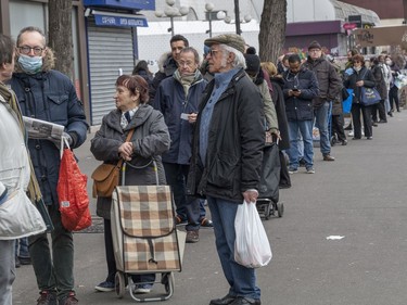 People queue in front of a supermarket ahead of the enforced quarantine starting at noon on Tuesday in Paris, France. France imposed a nationwide lockdown to control the spread of COVID-19.