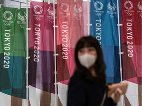 A woman walks past Tokyo 2020 Olympics banners on March 19, 2020 in Tokyo, Japan.