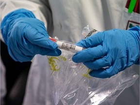 A lab worker handles a vial.
