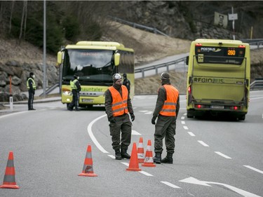 Police and soldiers of the Austrian army at a roadblock stop buses from driving out of the Panznautal valley following the imposition of a quarantine due to the coronavirus on March 14, 2020 near Ischgl, Austria. The ski resort towns of Sankt Anton and Ischgl are both under quarantine and many ski resorts in the region have been closed. The Austrian government is pursuing aggressive measures, including closing schools, cancelling events and shuttering shops except for grocery stores and pharmacies in an effort to slow the ongoing spread of the coronavirus.