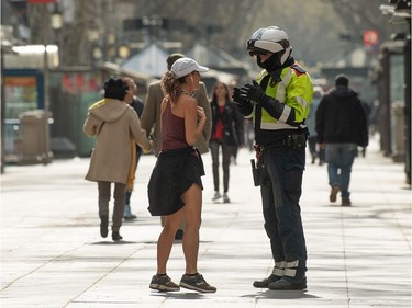 A Catalan Autonomous police officer, Mosso d'Esquadra, halts a woman who was jogging through Las Ramblas on March 15, 2020 in Barcelona, Spain. As part of the measures against the virus expansion the Government has declared a 15-day state of emergency which will come into effect today. The Government of Spain has strengthened up its quarantine rules, shutting all commercial activities except for pharmacies, food shops, gas stations, tobacco stores and news kiosks in a bid to stop the spread of the novel coronavirus, as well as transport. Spaniards must stay home except to go work but working for home is recommended, going to buy basic things as food or pharmacy products is allowed but it must be done individually. The number of people confirmed to be infected with the coronavirus (COVID-19) in Spain has increased to at least 6,391, with the latest death toll reaching 196, according to the countrys Health Ministry.