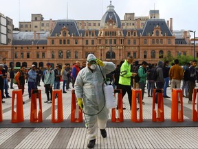 Cleaning staff are seen after using disinfectants at subway entrances as people line up to enter the Constituci—a transfer centre, one of the most important in the city, in response to the outbreak of coronavirus disease (COVID-19) in Buenos Aires, Argentina March 19, 2020. (REUTERS/Matias Baglietto)