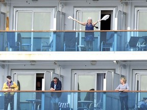 A woman gestures as other people look on from aboard the Grand Princess cruise ship, operated by Princess Cruises, as it maintains a holding pattern about 25 miles off the coast of San Francisco, California on March 8, 2020.