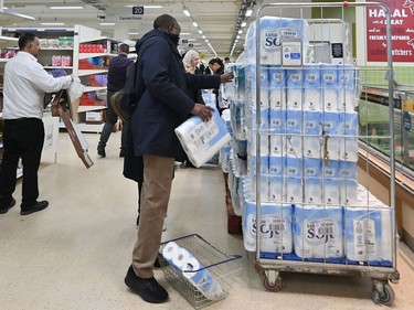 A woman buys toilet paper at a supermarket in London on March 14, 2020, as consumers worry about product shortages, leading to the stockpiling of household products due to the outbreak of the novel coronavirus COVID-19.