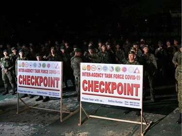 Soldiers stand guard as they wait inside the military headquarters to be deployed in major thoroughfares, in Manila on March 14, 2020. - Manila will impose a night-time curfew in the city of 12 million, officials said on March 14, as the Philippines steps up efforts to curb the spread of the new coronavirus.