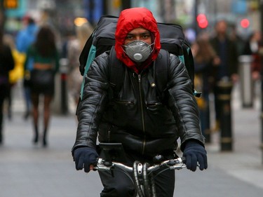 A delivery man wearing a mask cycles in Cardiff, Wales on March 14, 2020.