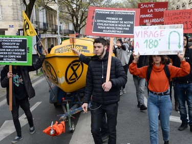 Protesters hold banners reading "180 degree turn " and "coronavirus pandemic, the first step in the collapse of our civilization if we do not revolt today" during a demonstration for climate change in Bordeaux, despite the authorities' recommendations to limit gatherings amid the outbreak of COVID-19, caused by the novel coronavirus, on March 14, 2020.