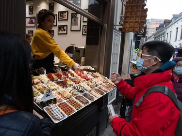 Asian tourists wearing protecting face mask buy candies in Brussels, on March 14, 2020 amid the outbreak of COVID-19, caused by the novel coronavirus. -