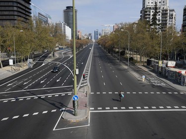 A woman crosses the usually busy La Castellana avenue in Madrid on March 15, 2020. - France and Spain are the latest European nations to severely curtail people's movements as countries across the Americas and Asia impose travel restrictions in a widening crisis over coronavirus, as the number of infections around the world passed 150,000, with nearly 6,000 deaths.