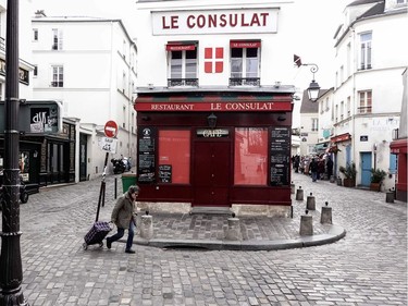 A woman walks past closed restaurants and shops in the Montmartre area in Paris on March 15, 2020, a day after France ordered the closure of all non-essential public places including restaurants and cafes, amid the COVID-19 outbreak, caused by the novel coronavirus. - France will progressively reduce long-distance train, bus and plane travel over the coming days in a bid to limit the spread of the coronavirus, the government announced on March 15. The country has already shuttered cafes, restaurants, schools and universities and urged people to limit their movements.