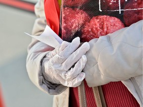 A women wears protective gloves outside a supermarket in England. They're not really helping her.