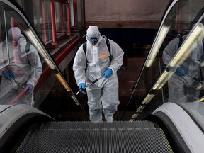 A member of the Military Emergencies Unit (UME) carries out a general disinfection at the Nuevos Ministerios Metro Station in Madrid on March 18, 2020. - Spain is the fourth hardest-hit nation in the world by the coronavirus pandemic, with over 13,700 confirmed cases and the number of deaths rising to almost 600. The nation of around 46 million people is on a near total lockdown since the weekend, with people allowed out of their homes only to buy food, medicine or to go to work if they can not do so from home.