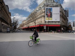 At least they'er staying home now: A man rides his bicycle across an empty street in front of the Galeries Lafayette in Paris, on March 18, 2020. Considering what they saw happen in Italy, the French have been late to the idea of self-isolation.