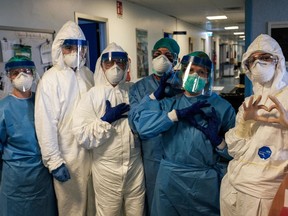 A group of nurses wearing protective mask and gear pose for a group photo prior to their night shift on March 13, 2020 at the Cremona hospital, southeast of Milan, Lombardy, during the country's lockdown aimed at stopping the spread of the COVID-19 (new coronavirus) pandemic. - After weeks of struggle, they're being hailed as heroes. But the Italian healthcare workers are exhausted from their war against the new coronavirus. (Photo by Paolo MIRANDA / AFP) / RESTRICTED TO EDITORIAL USE - MANDATORY CREDIT "AFP PHOTO / PAOLO MIRANDA" - NO MARKETING - NO ADVERTISING CAMPAIGNS - DISTRIBUTED AS A SERVICE TO CLIENTS