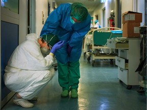 A nurse wearing protective mask and gear comforts another as they change shifts on March 13, 2020 at the Cremona hospital, southeast of Milan, Lombardy, during the country's lockdown aimed at stopping the spread of the COVID-19 (new coronavirus) pandemic.