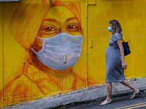 A pregnant woman wearing a face mask as a precautionary measure walks past a street mural in Hong Kong, on March 23, 2020.