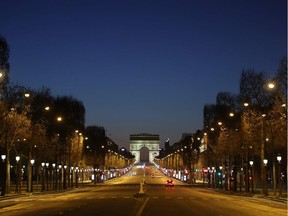 A picture shows the empty Champs-Elysees Avenue and the Arc de Triomphe in Paris, at night on March 24, 2020, on the eight day of a lockdown aimed at curbing the spread of the COVID-19 (novel coronavirus) in France.