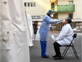 A pharmacist has samples taken at a COVID-19 screening centre reserved for health professionals on March 27, 2020 in Paris, as the country is under lockdown to stop the spread of the Covid-19 pandemic caused by the novel coronavirus. (Photo by FRANCK FIFE / AFP)
