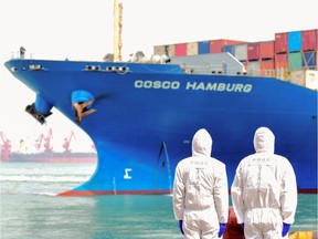 China's immigration inspection officers wearing protective suits look at a cargo ship at a port in Qingdao in China's eastern Shandong province on March 31, 2020.