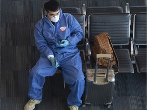 A passenger wears disposable coveralls, face mask and protective gloves as he waits for a flight at Halifax Stanfield International Airport in Enfield, N.S.