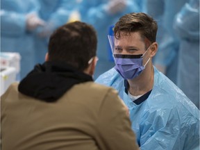 A health care worker speaks to a test patient, a staff member portraying the role of a patient to ensure the assessment systems are working, at an assessment table as they prepare for the opening of the COVID-19 Assessment Centre at Brewer Park Arena in Ottawa, during a media tour on Friday, March 13, 2020.