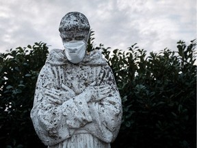 A protective mask on the face of a statue of Italy's patron saint, St. Francis, in San Fiorano.