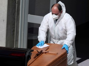 A funeral worker wearing a protective suit carries a coffin out of the morgue at Severo Ochoa Hospital, during the coronavirus disease outbreak in Leganes, Spain, March 26, 2020.