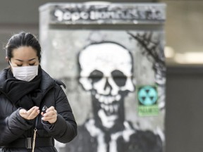 A pedestrian wearing a mask walks on Spadina Avenue in downtown Toronto on March 19, 2020.