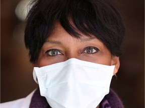 A nurse waits at the entrance of a hospital.